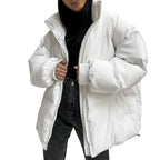 Person wearing a white puffer jacket over a black outfit against a plain background