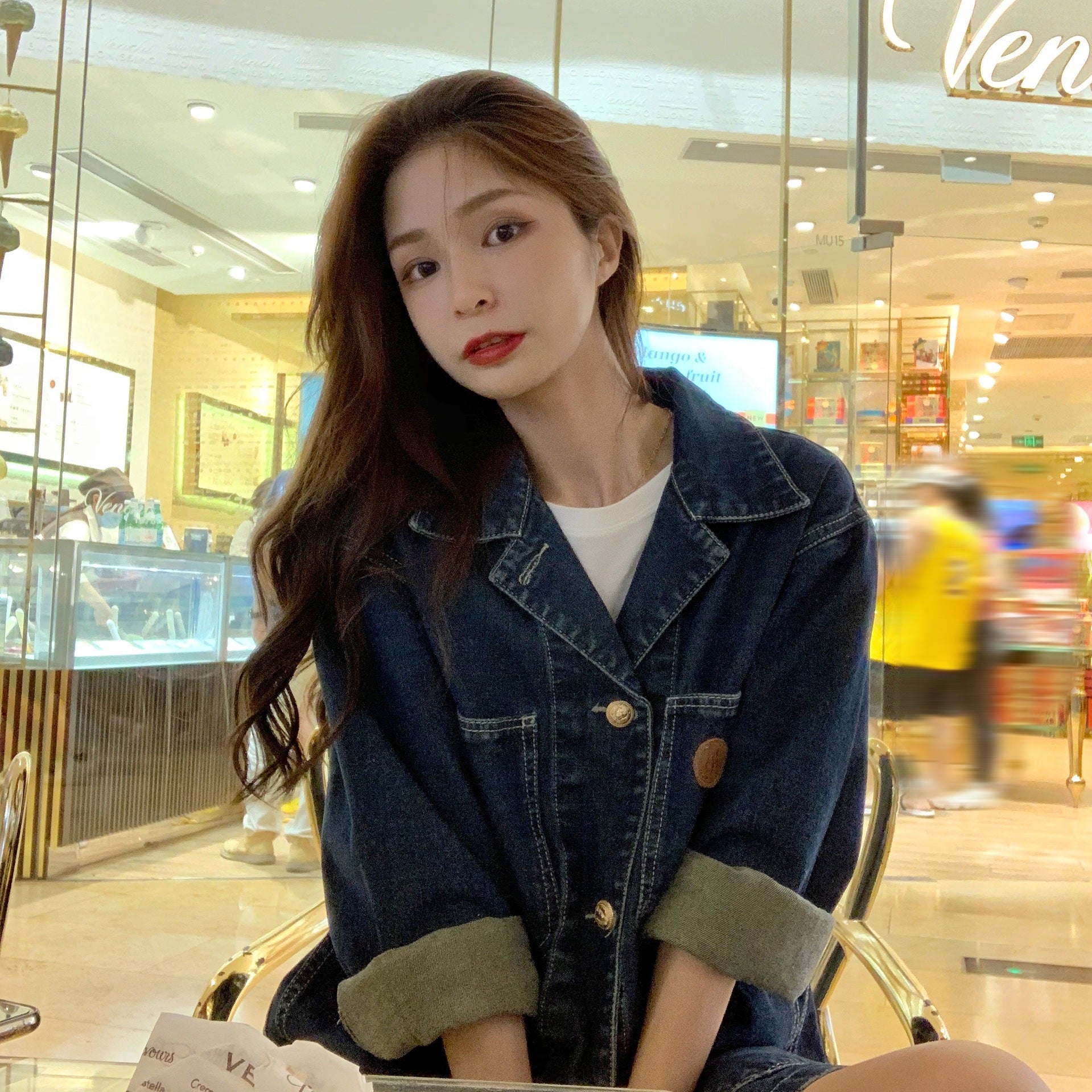Woman wearing a denim jacket in a shopping mall setting