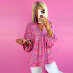 Woman taking a mirror selfie wearing a pink floral blouse against a pink background