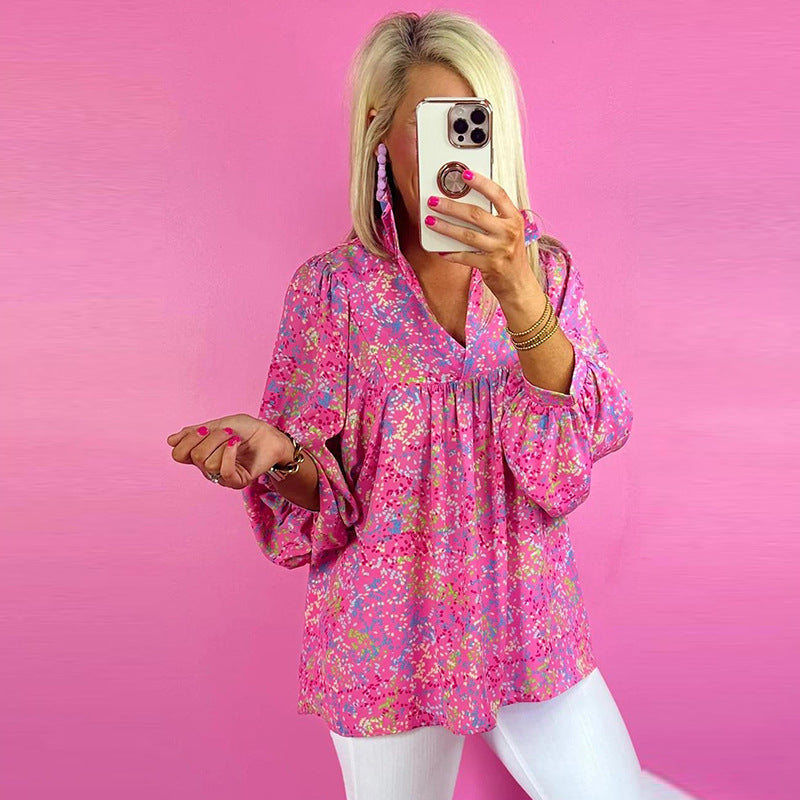 Woman taking a mirror selfie wearing a pink floral blouse against a pink background