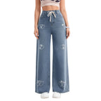 Wide-leg denim pants with heart patterns worn by a person indoors.