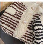 Close-up of a knitted cardigan with brown and white striped pattern and pearl buttons.