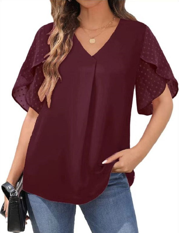 Woman wearing a burgundy blouse with ruffled sleeves on a white background