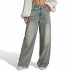 Person wearing light blue jeans on a beige background