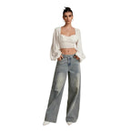 Woman wearing a white top and blue jeans against a beige background