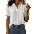 Person wearing a white button-up shirt and blue jeans against a plain background