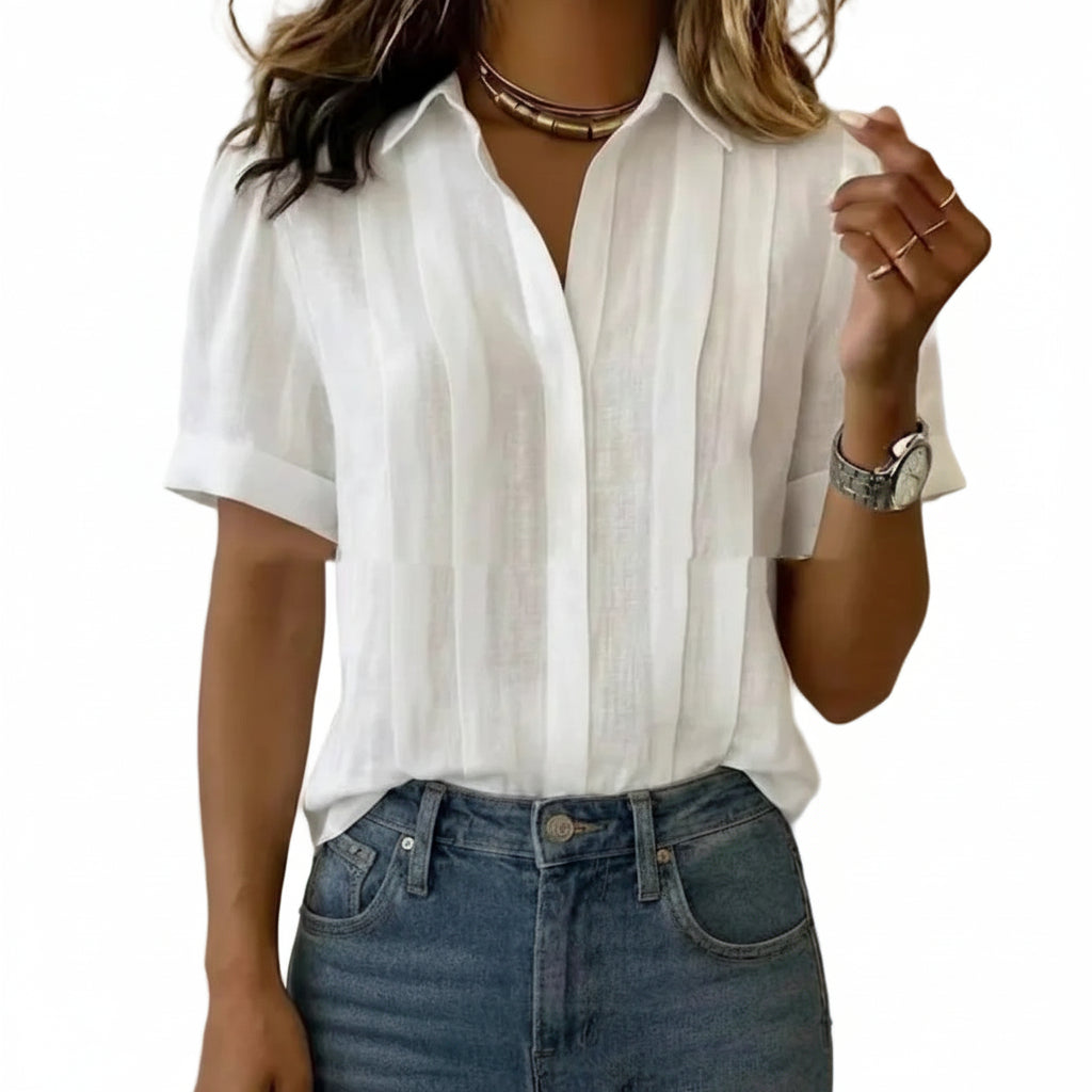 Person wearing a white button-up shirt and blue jeans against a plain background