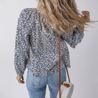 Person wearing a floral blouse and jeans, holding a straw bag against a plain background