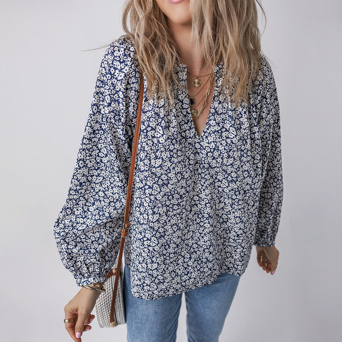 Woman wearing a floral blouse and jeans with a neutral background