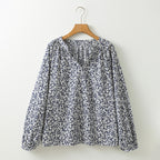 Floral blouse on a wooden hanger against a white background