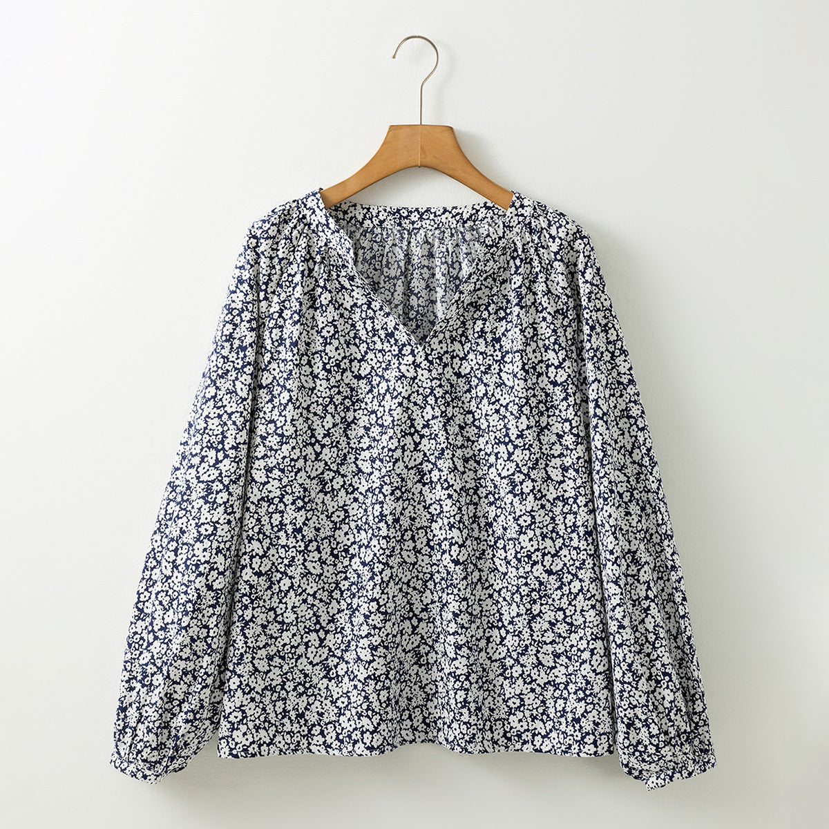 Floral blouse on a wooden hanger against a white background