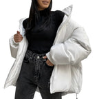 Person wearing a white puffer jacket over a black top and gray jeans on a plain background
