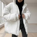 Person wearing a white puffer jacket over a black outfit against a plain background