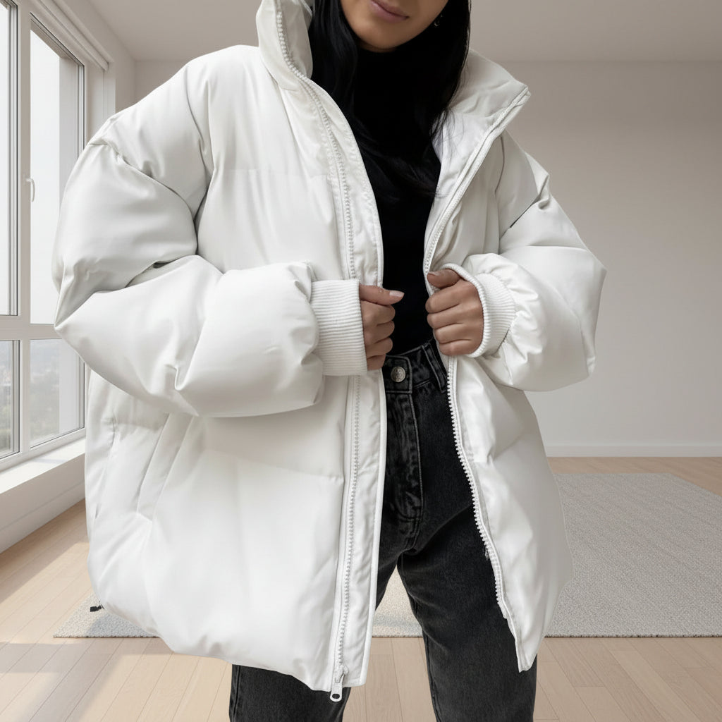 Person wearing a white puffer jacket over a black outfit against a plain background