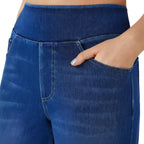 Close-up of blue jeans with a hand in the pocket against a white background