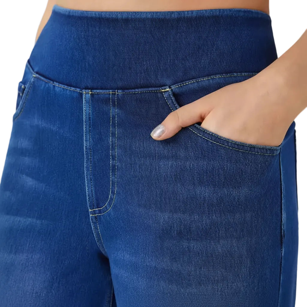 Close-up of blue jeans with a hand in the pocket against a white background