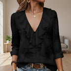 Black ruffled blouse worn by a person with a blurred background