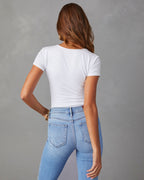 Person wearing a white t-shirt and light blue jeans against a gray background