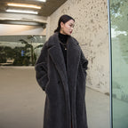 Woman wearing a long gray coat standing in an urban setting.