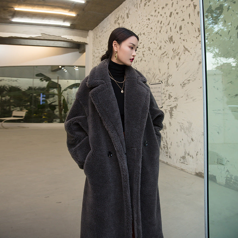 Woman wearing a long gray coat standing in an urban setting.